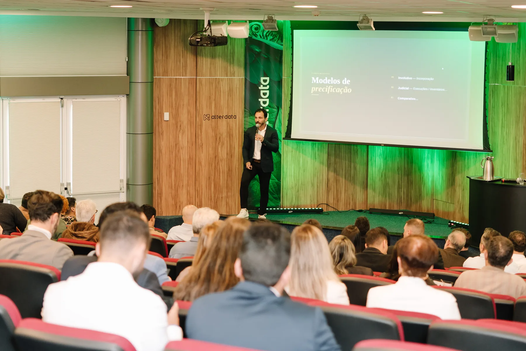 Palestrante apresentando o slide "Modelos de precificação" na 1ª edição